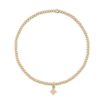 Gold beaded stretch bracelet with a small cross charm