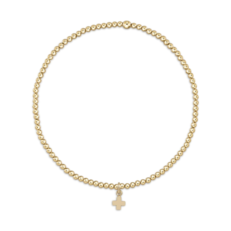 Jewelry bracelet a delicate gold beaded bracelet with uniform round beads and a small gold cross charm against a plain white background