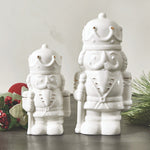 Two white ceramic nutcracker figurines with gold accents