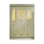 Santa Barbara Design Studio brushed gold metal cheese tool set featuring a knife, spatula, and wedge spreader with distinctive open loop handles presented in a sage green display box