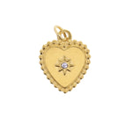 Gold heart pendant with a beaded border surrounding a central starburst holding a clear gemstone