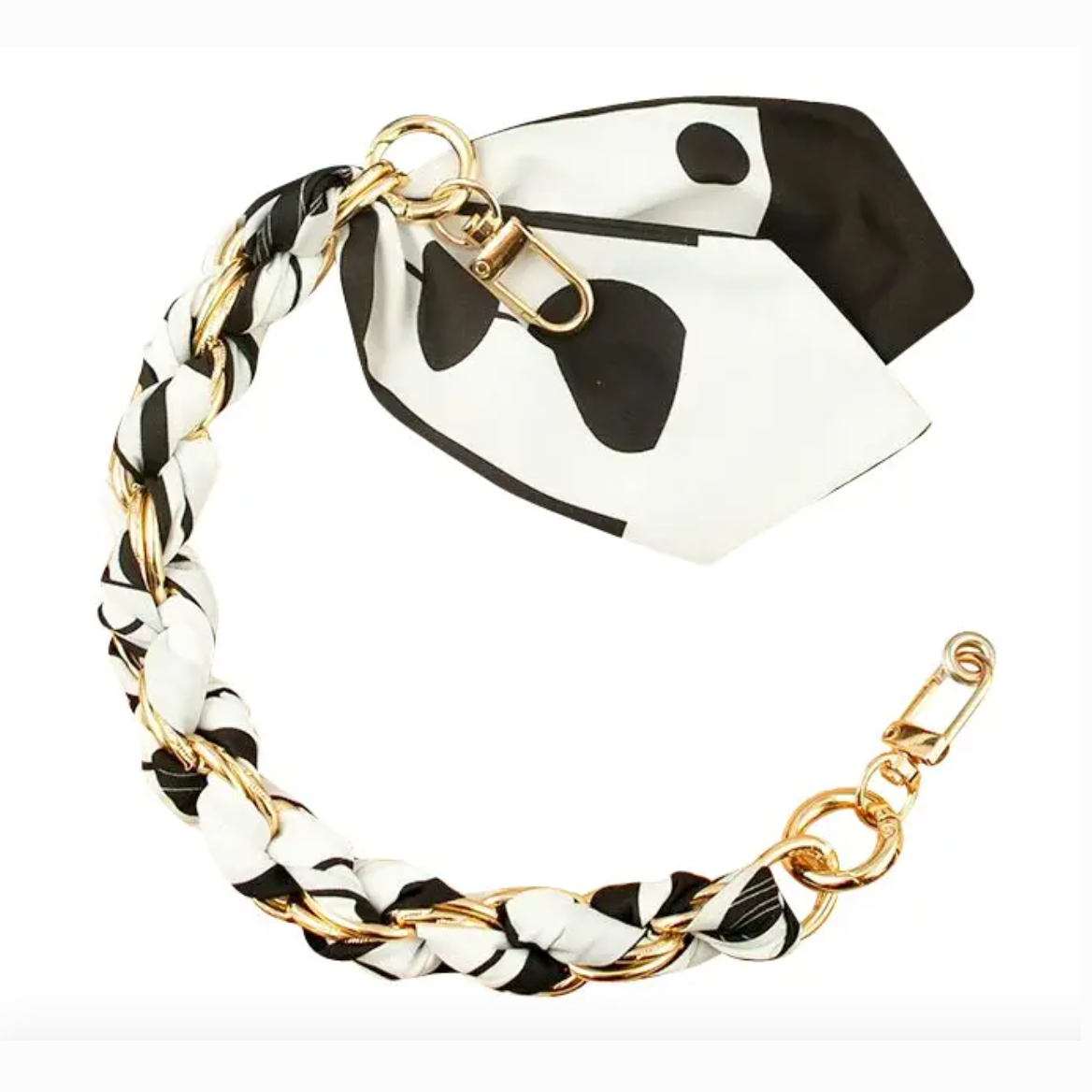 A decorative bag strap featuring a gold-tone metal chain intricately interwoven with black and white fabric displaying an irregular spot pattern and secured by two clip clasps
