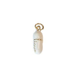 Photograph of a small glossy white capsule charm featuring a gold bail, the word 'love' delicately inscribed vertically in gold script, and a subtle gold band