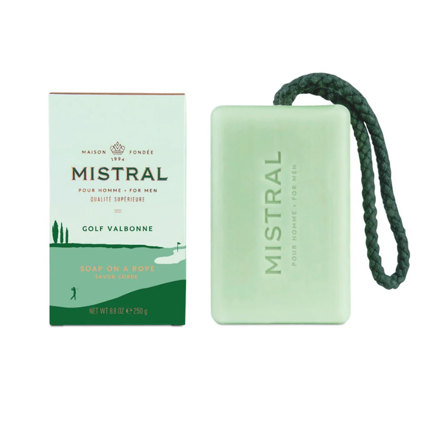 Product photograph by Mistral of the Golf Valbonne soap on a rope featuring a mint green bar with a dark green braided cord and packaging showing a stylized golf course with cypress trees and a golfer silhouette