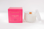 Aroma Avenue Good Vibes candle in a pink box next to a crystal glass candle jar with a lid
