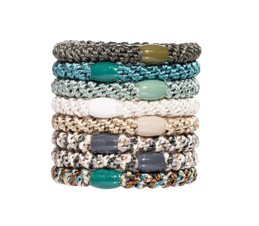 Eight L. Erickson elastic hair ties stacked vertically on a white background, displaying braided textures in a diverse color palette including olive green, vibrant teal, off-white, and multi-toned patterned designs
