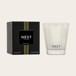 Product photo by NEST New York featuring a Grapefruit scented candle in a clear glass votive with frosted stripes alongside its black box accented with green and gold vertical stripes