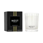 NEST New York Grapefruit scented candle in a clear glass holder with white frosted vertical stripes alongside its black box adorned with green and gold horizontal stripes