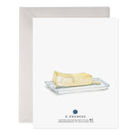 Watercolor illustration of a stick of butter with a face relaxing on a small white dish