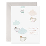 Greeting card with watercolor illustrations of babies in teacup hot air balloons and text Congrats on your new arrival