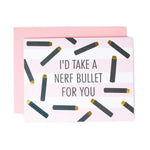 Greeting card featuring the text I'D TAKE A NERF BULLET FOR YOU on a pink and white striped background adorned with black shapes with gold tips resembling toy darts, partially visible over a solid pink envelope