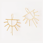 A pair of gold-toned metal earrings in abstract sunburst shapes with an openwork geometric design on a plain white background one earring tilted