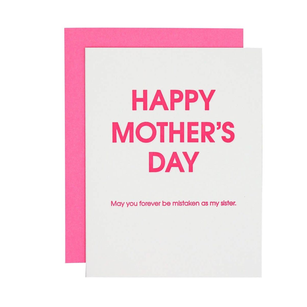 Greeting card showing a white card with bold hot pink lettering for HAPPY MOTHER'S DAY and the smaller phrase May you forever be mistaken as my sister, set against a vibrant pink envelope