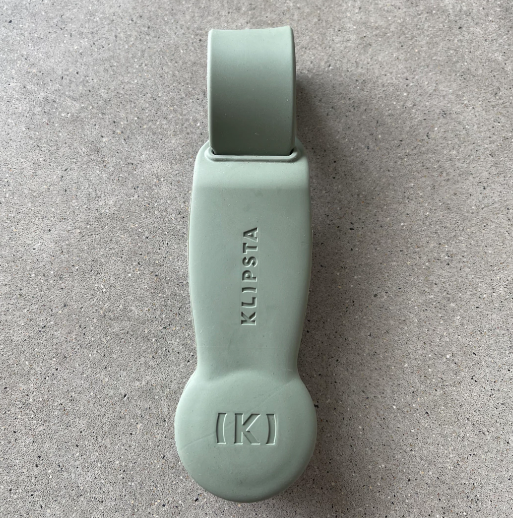 Sage green Klipsta hat clip on a grey stone surface