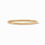Gold bangle bracelet with a hammered exterior and geometric cutout pattern on the inner band