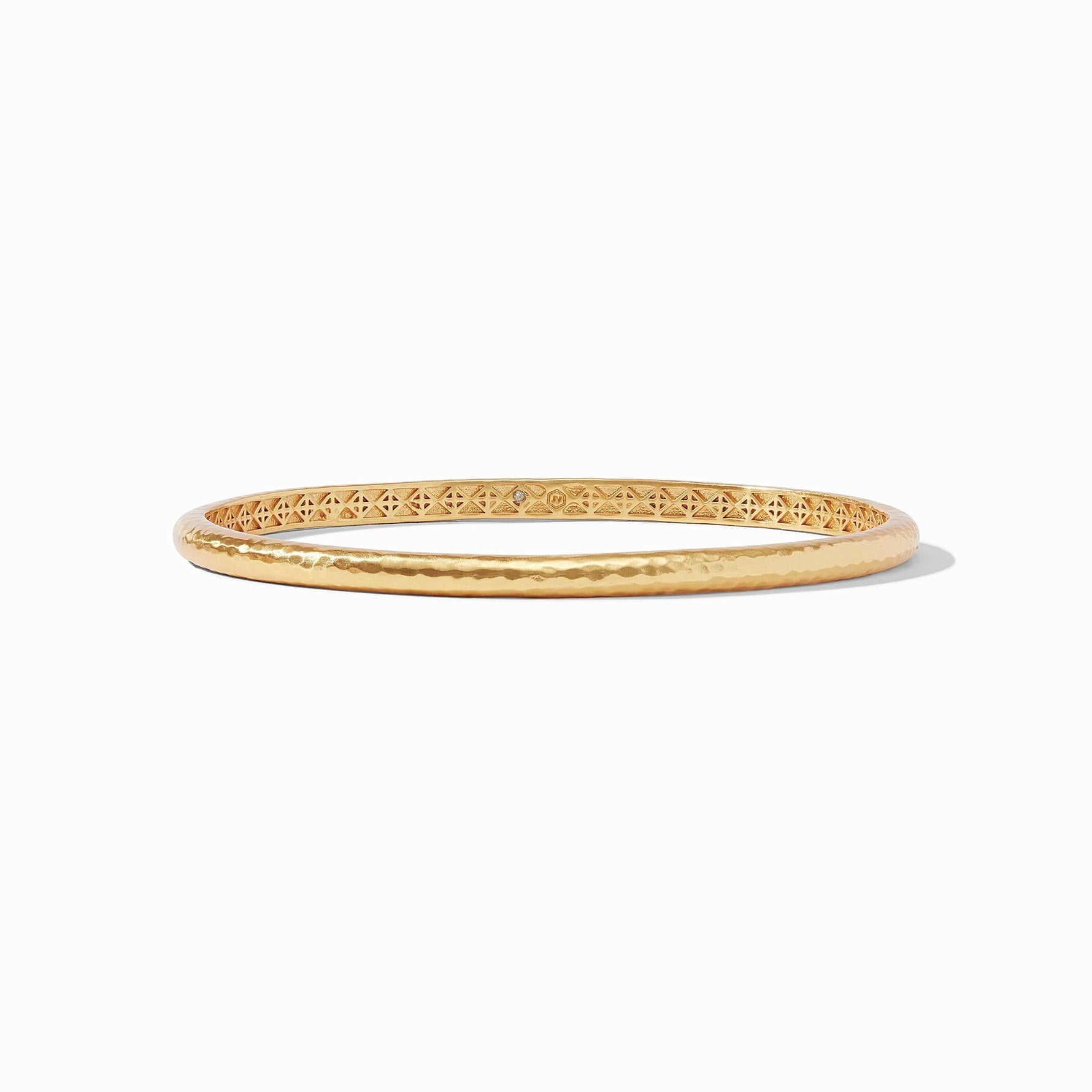 Gold bangle bracelet with a hammered exterior and geometric cutout pattern on the inner band