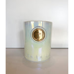 Iridescent ceramic candle vessel featuring a prominent gold circular cross emblem and embossed Sea La Vie text on a plain white background