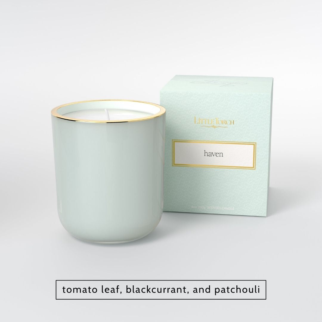 Light green candle in a glass jar with gold rim next to matching box labeled haven