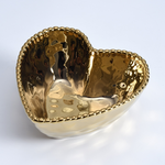 A gold heart-shaped bowl featuring a hammered, highly reflective interior and a decorative beaded rim on a white background