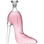 Clear glass decanter shaped like a high-heeled stiletto shoe filled with pink liquid and topped with a dazzling diamond-shaped stopper