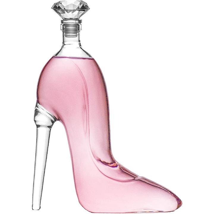 Clear glass decanter shaped like a high-heeled stiletto shoe filled with pink liquid and topped with a dazzling diamond-shaped stopper