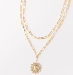 Gold layered paperclip chain necklace with a textured circular pendant featuring the letter K