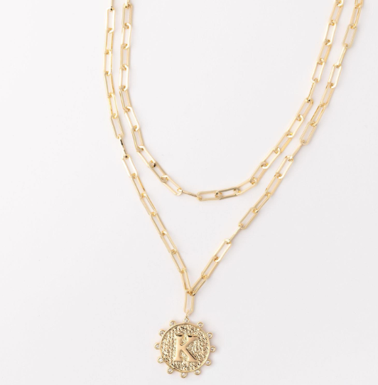 Gold layered paperclip chain necklace with a textured circular pendant featuring the letter K