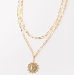 Gold layered paperclip chain necklace with a textured circular pendant featuring the letter E