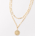 Gold layered paperclip chain necklace with a textured circular pendant featuring the letter H