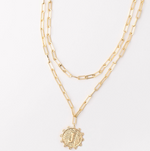 Gold layered paperclip chain necklace with a textured circular pendant featuring the letter J