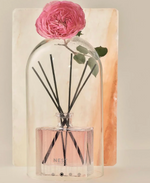 Nest New York reed diffuser in a glass cloche with a pink rose