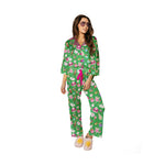 Full-length studio shot of a woman in festive green holiday pajamas with pink piping, a pink drawstring, and fuzzy pink sun slippers, adorned with Nutcrackers, ballet dancers, and gifts, wearing sunglasses