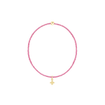 Handcrafted jewelry by Gigi Clozeau featuring a vibrant pink resin beaded bracelet centered on a black background with a small 18k yellow gold cross charm and a single polished gold sphere bead