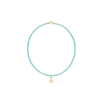 Beaded jewelry turquoise bracelet centered on a black background featuring small aqua seed beads, a single gold ball accent, and a polished yellow gold cross charm pendant