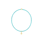 Beaded jewelry featuring a vibrant turquoise seed bead bracelet centered on a solid black background with a polished gold accent bead and a small dangling gold cross charm