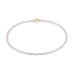 Stretch bracelet made of small iridescent white beads with a single gold bead