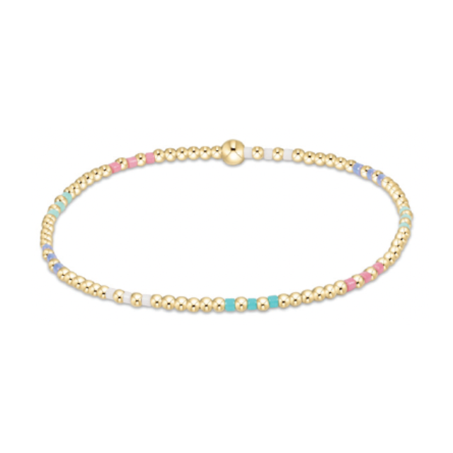 A delicate gold beaded bracelet with a single larger gold bead and colorful enamel sections in pastel pink, light blue, lavender, and white