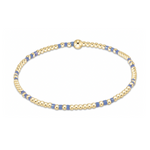 Delicate gold-tone beaded bracelet featuring small round beads interspersed with rectangular periwinkle blue beads and a central spherical gold bead