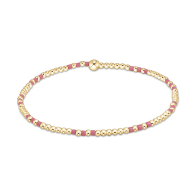Minimalist beaded bracelet featuring alternating small gold spherical beads and fuchsia rectangular beads, secured by a larger gold spherical clasp, presented on a clean white background