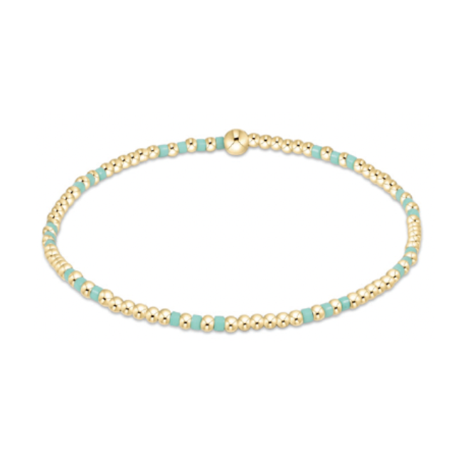 A delicate beaded bracelet featuring numerous small gold spheres interspersed with flat rectangular turquoise beads and a prominent gold spherical clasp