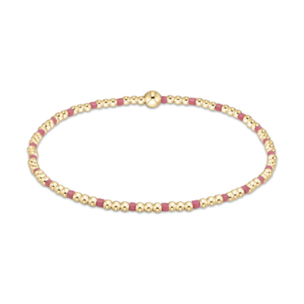A delicate bracelet featuring alternating tiny spherical gold beads and short rectangular fuchsia pink beads, secured with a larger spherical gold clasp, isolated on a white background