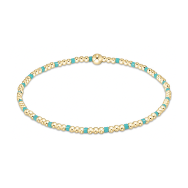 A minimalist beaded bracelet featuring small gold spheres alternating with vibrant turquoise beads and a larger gold spherical bead
