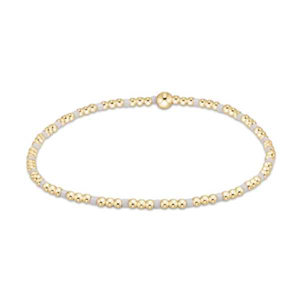Jewelry a minimalist stretch bracelet featuring small round gold beads alternating with light grey segments and a prominent central gold bead accent