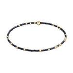 Delicate beaded bracelet crafted with matte black seed beads and shiny gold spherical beads, accented by a central flattened gold disc