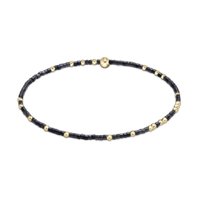 Delicate beaded bracelet crafted with matte black seed beads and shiny gold spherical beads, accented by a central flattened gold disc
