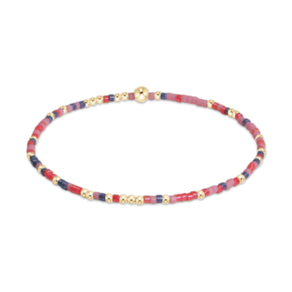 A delicate beaded bracelet featuring small gold spherical beads interspersed with colorful red, pink, and navy blue cylindrical seed beads