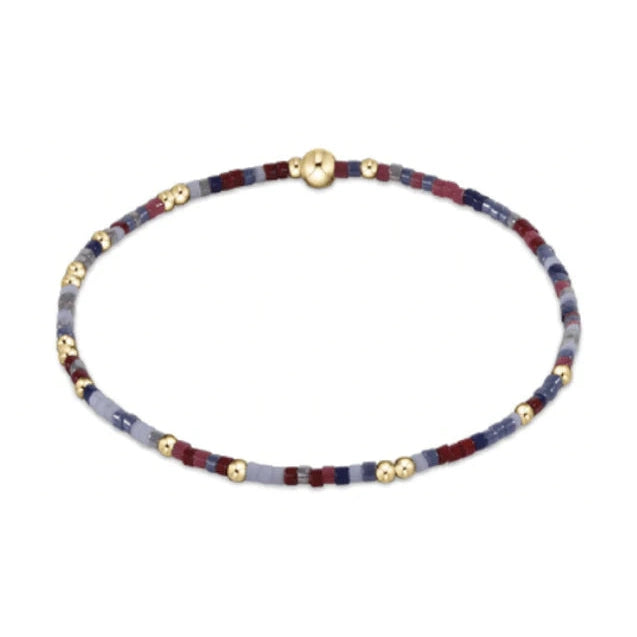 Delicate beaded bracelet featuring tiny square beads in red blue and grey colors accented by small round gold beads and a spherical gold clasp