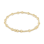 A polished yellow gold beaded stretch bracelet featuring alternating sizes of smooth spherical beads on a white background