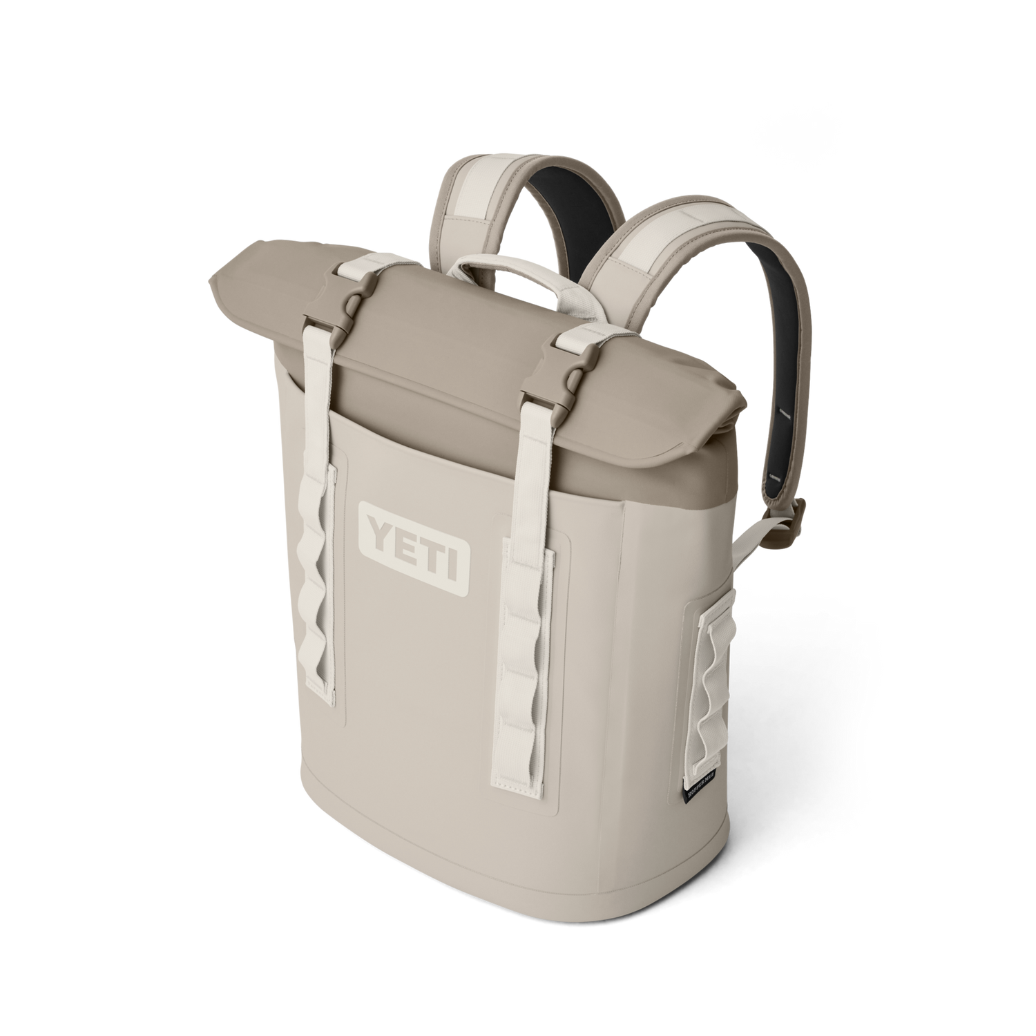 Digital render of a tan YETI Hopper M20 backpack soft cooler featuring a prominent YETI logo, roll-top closure with white straps and buckles, and padded shoulder straps against a black studio background