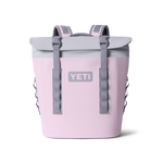 Blush pink YETI cooler backpack featuring a light grey roll-top closure, grey buckle straps, padded shoulder straps, and a prominent YETI logo